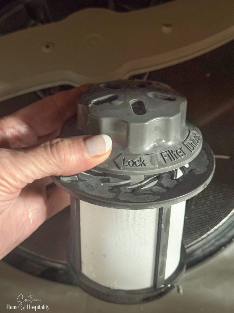 Dishwasher filter removed from the bottom of a dishwasher for cleaning and maintenance.