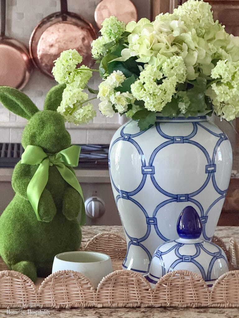 Spring vignette with blue and white ginger jar, green flowers, and moss bunny