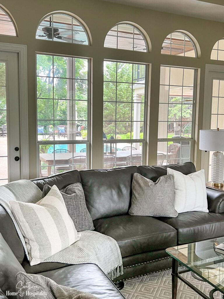 Dark leather sectional styled with neutral throw pillows in mixed textures and soft layered tones.