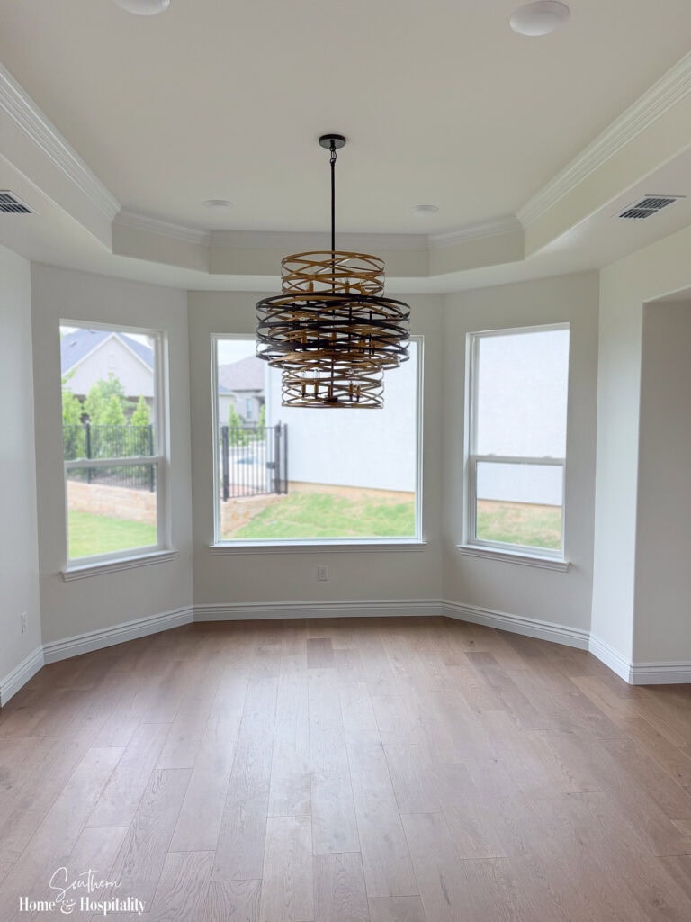 Empty breakfast room with wood floors, large windows, and statement light fixture awaiting furnishings