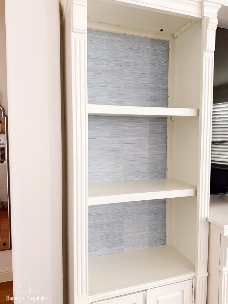 Peel-and-stick faux grasscloth wallpaper installed on a bookshelf back showing the centered seam before the shelf was styled.