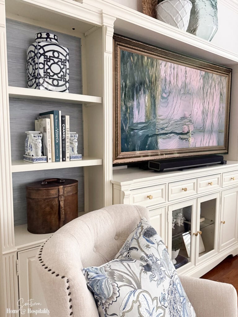 Angled view of entertainment center shelves with faux grasscloth wallpaper, showing how the textured shelf backs add depth and interest to displayed decor.