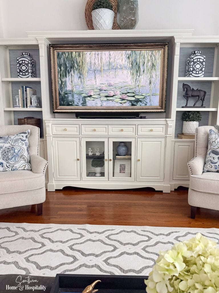Updated entertainment center with grasscloth wallpaper, blue and white decor, and styled shelves.