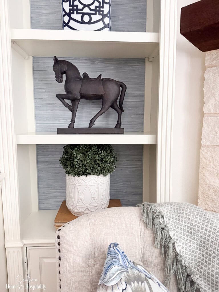 Faux grasscloth peel-and-stick wallpaper applied to the back of entertainment center shelves.