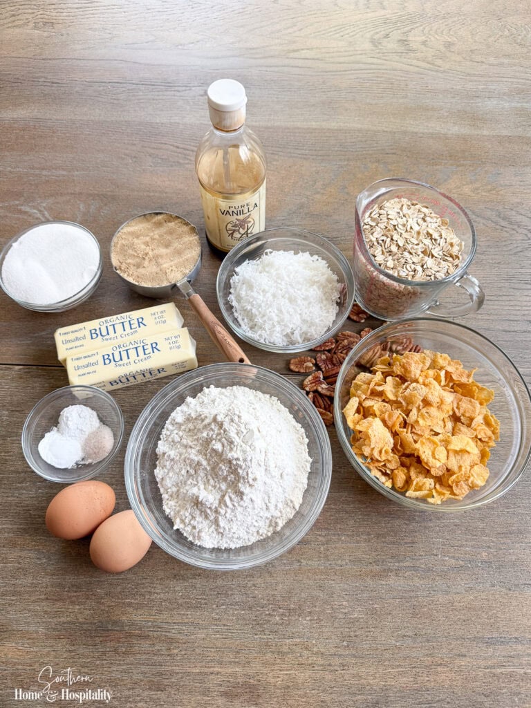 Ingredients for Old-Fashioned Ranger Cookies, including oats, cornflakes, coconut, pecans, flour, butter, eggs, and sugars.