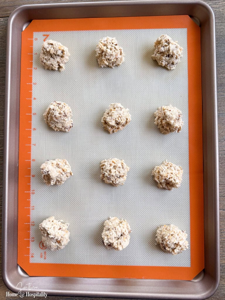 Scoops of Ranger Cookie dough on a parchment-lined baking sheet before baking.