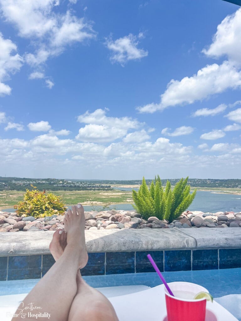 Swimming pool overlooking a peaceful lake surrounded by trees on a sunny summer afternoon.