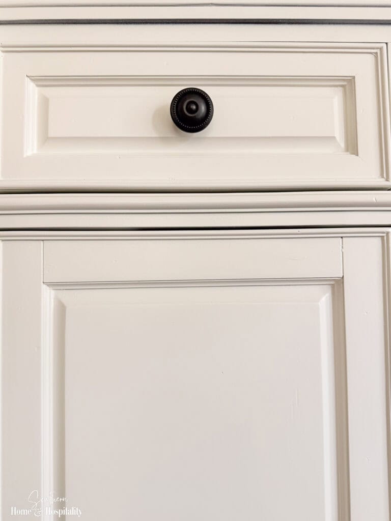 Original dark cabinet knob on the entertainment center before replacing the hardware.