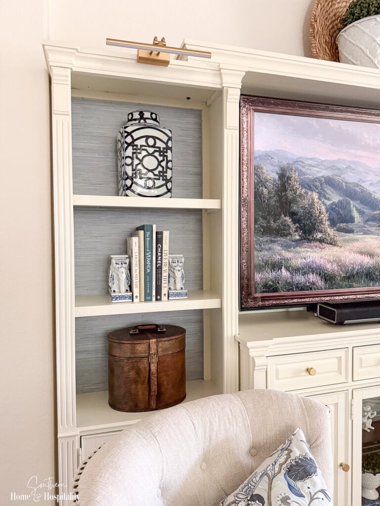 Rechargeable picture light mounted above entertainment center shelves with blue and white decor.
