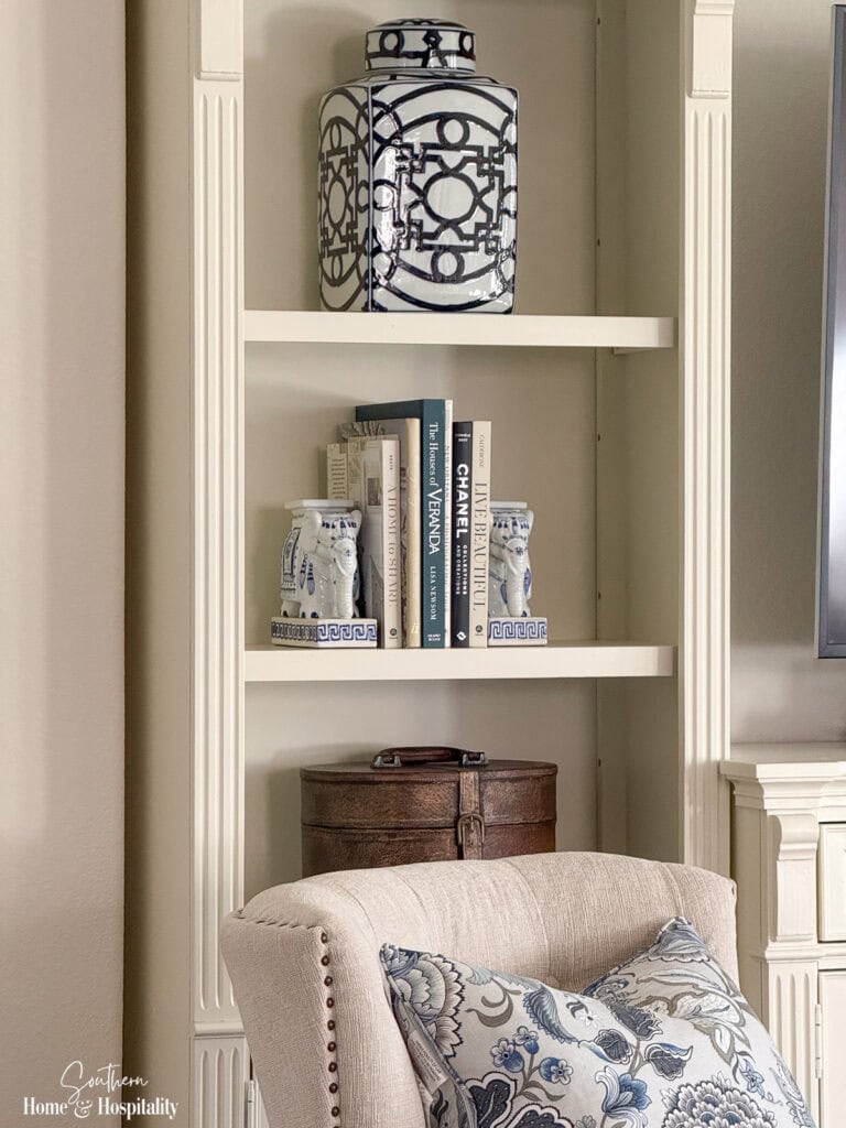 Entertainment center shelves styled with blue and white pottery, books, and a leather box.