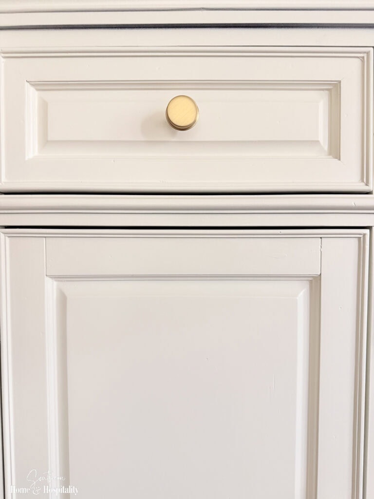 Brushed gold cabinet knob installed on the painted entertainment center.