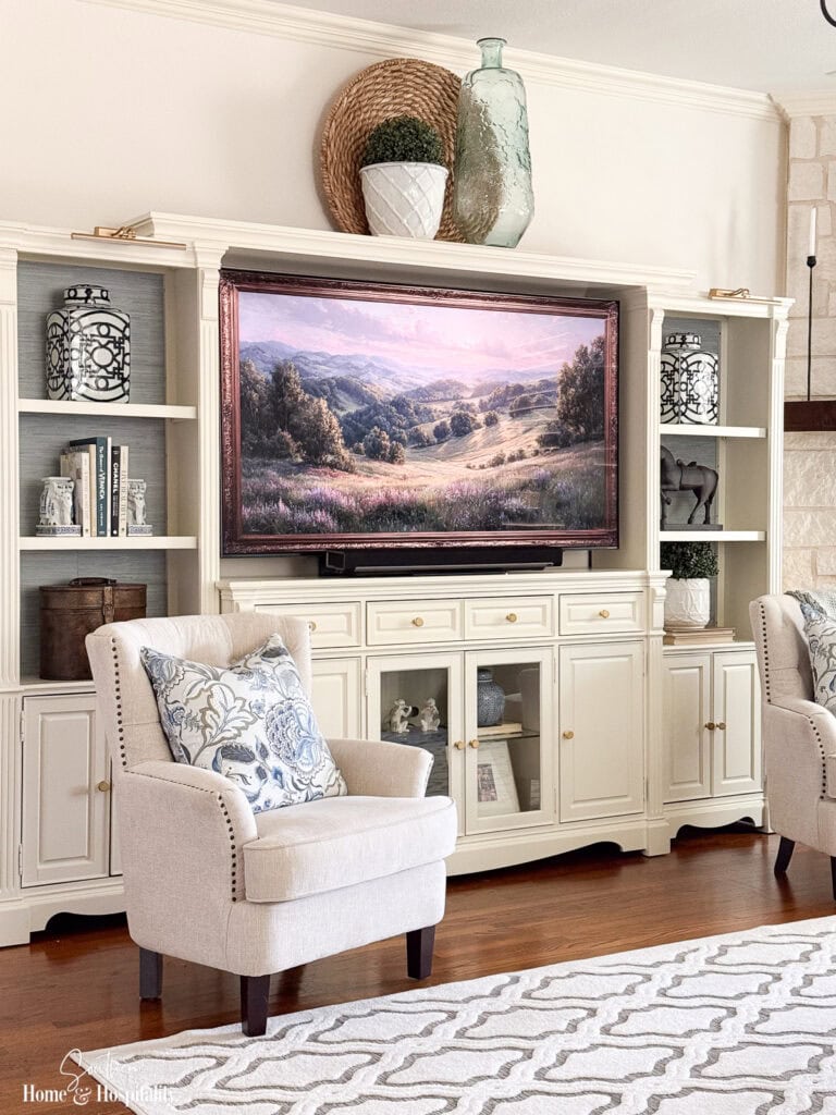 Side view of the updated entertainment center showing wallpaper, artwork, and layered shelf styling.