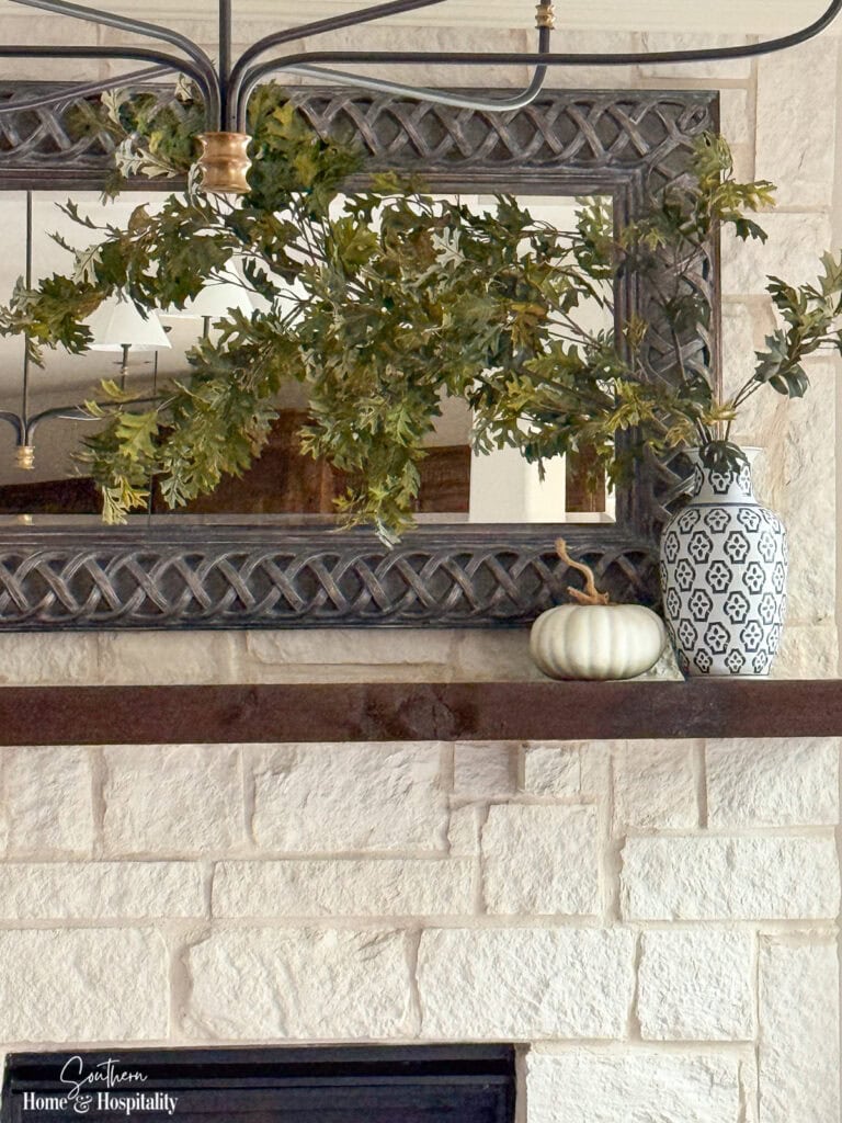 Ralph Lauren-inspired fall mantel with blue and white porcelain and tall oak branches over an Austin stone fireplace