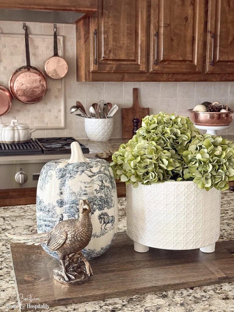 Fall kitchen decor with copper pans, white pumpkins, pinecones, blue and white, and warm wood