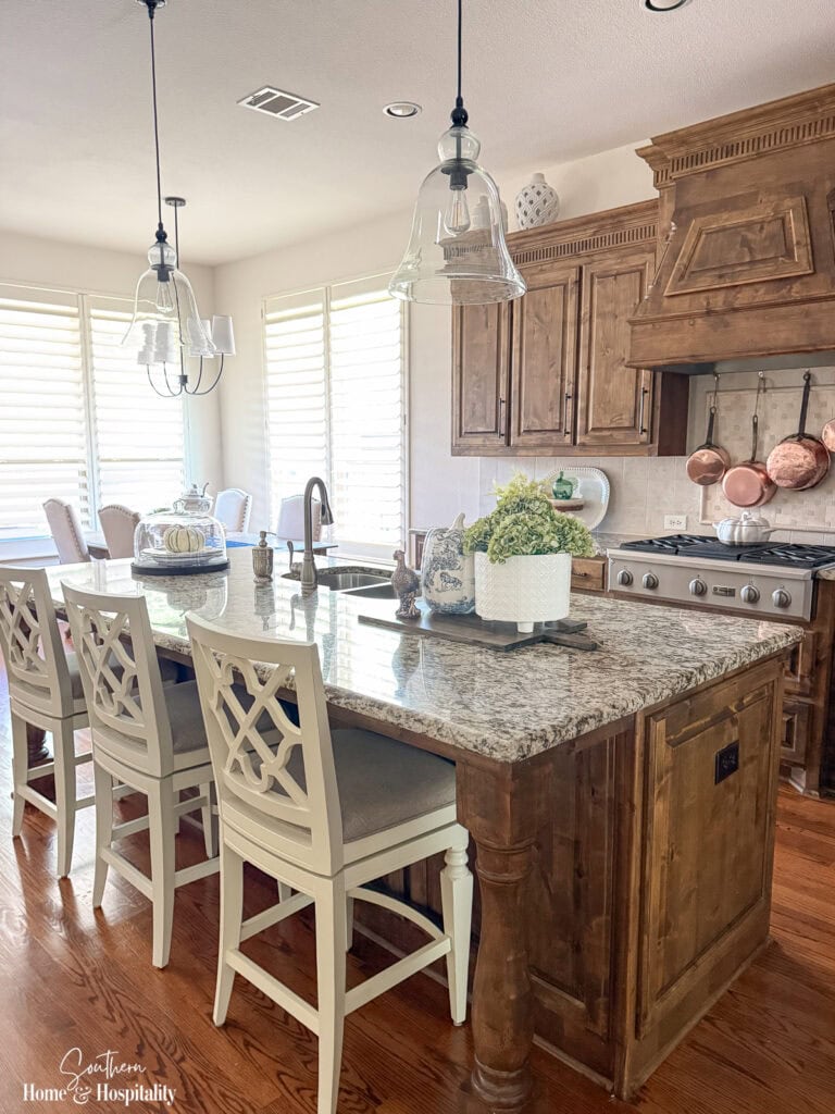 Fall kitchen with stained wood cabinets, copper accents, blue and white decor, and white pumpkins