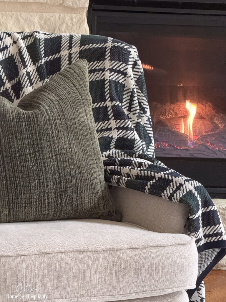 Ivory upholstered chair with olive velvet pillow and navy and green plaid throw for fall