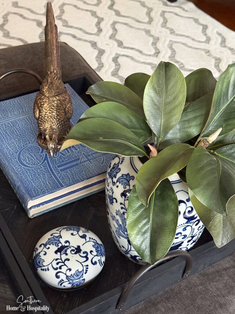 Blue and white vase with magnolia leaves and brass pheasant displayed on vintage LSU yearbooks
