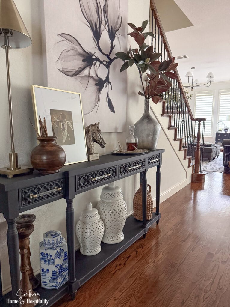 Ralph Lauren-inspired fall entry with black console, hunting accents, magnolia leaves, silver, warm wood, and pheasant feathers