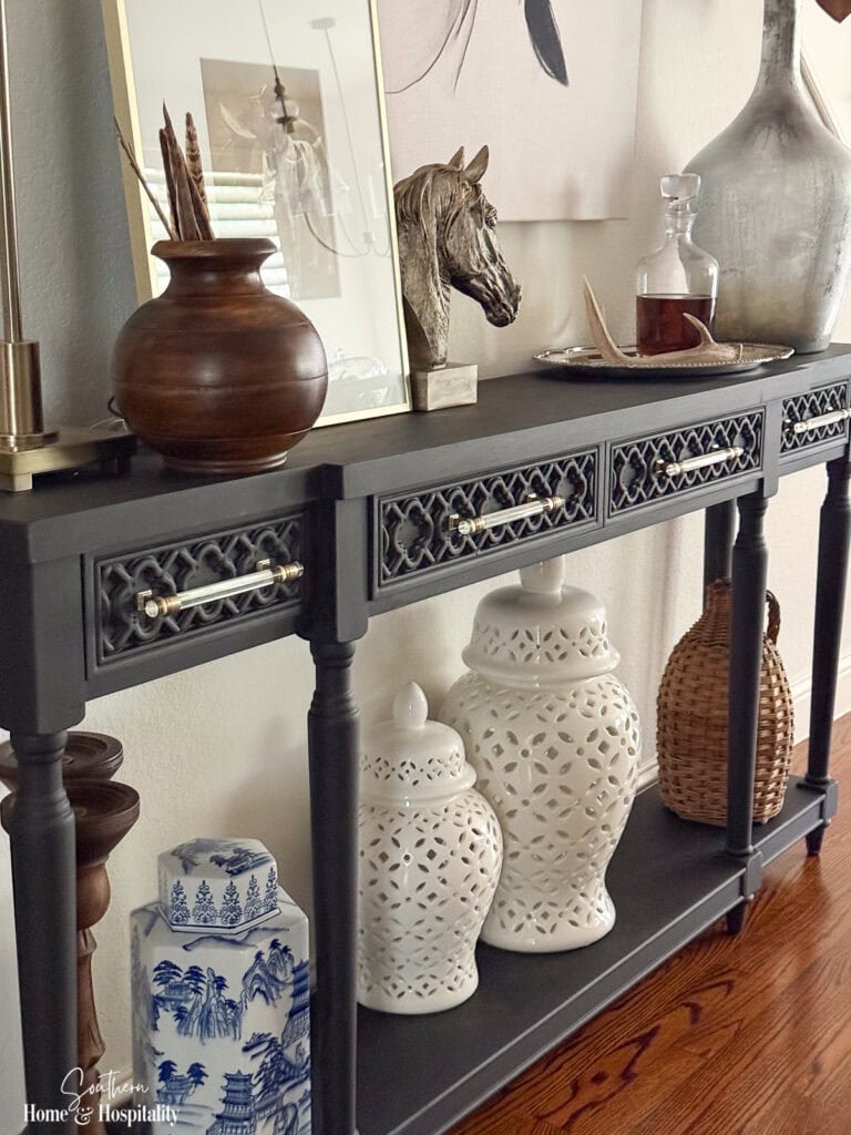 Black entry console styled with white and blue ginger jars, warm wood, and woven demijohn for fall