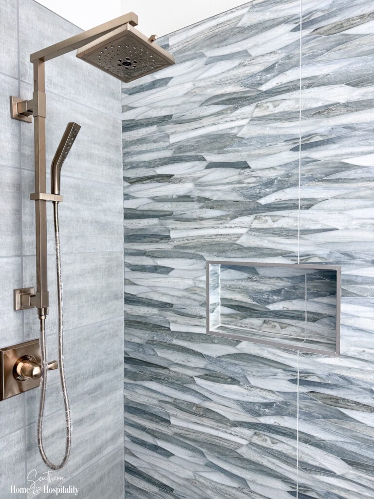 New home walk-in shower with tiled walls, built-in niche, and plumbing fixtures