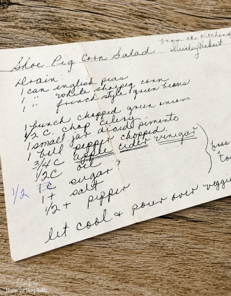 Old handwritten family recipe on worn paper resting on a weathered wood table.
