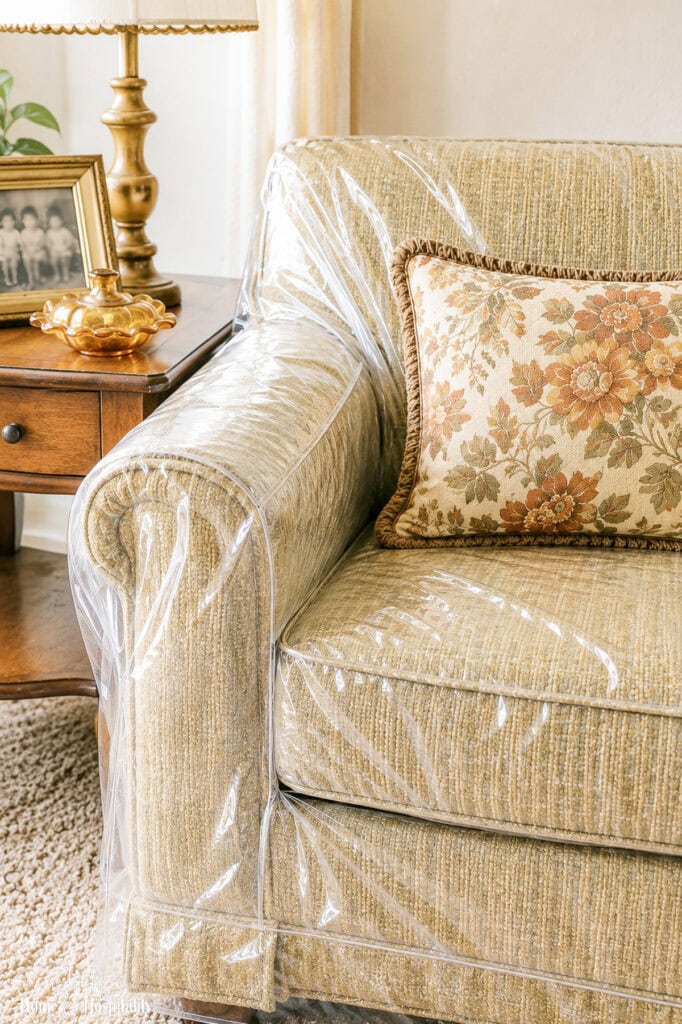 Close-up of a traditional sofa protected with a clear plastic furniture cover.