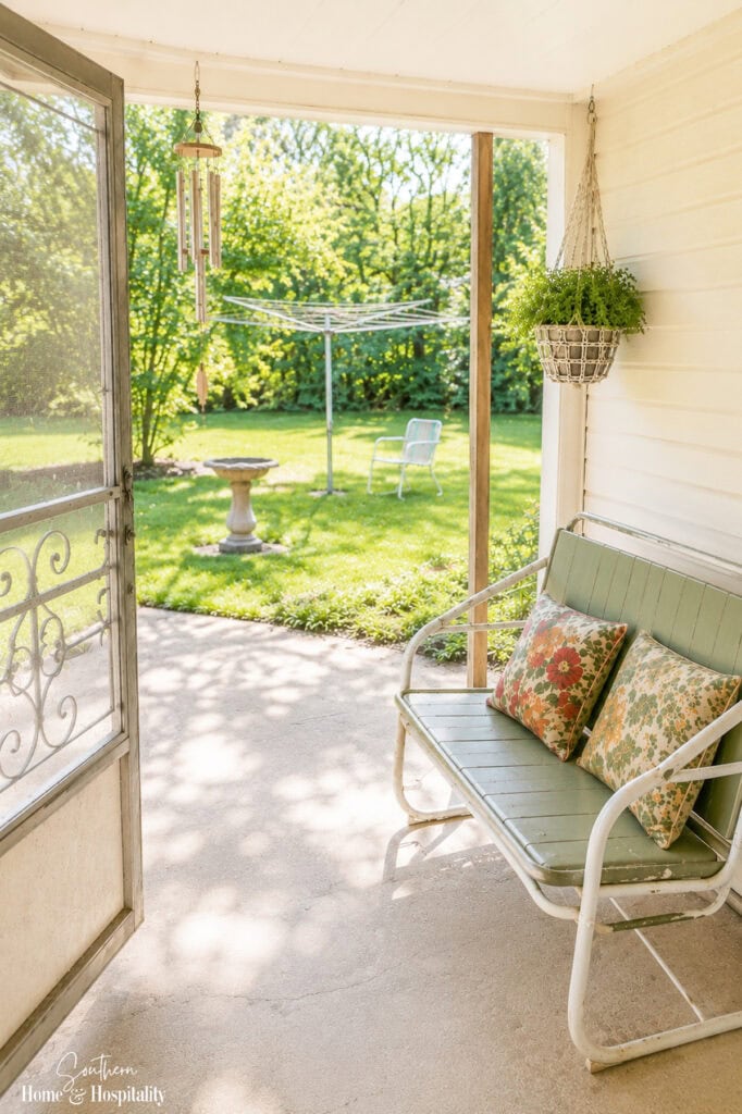 Nostalgic Southern porch with a vintage glider, hanging basket, and open screen door.