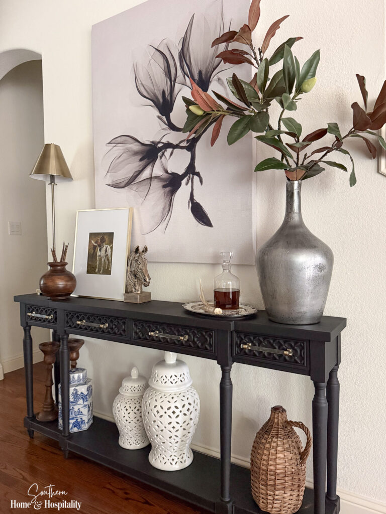 Tall faux magnolia branches arranged in a vase on a fall entry table