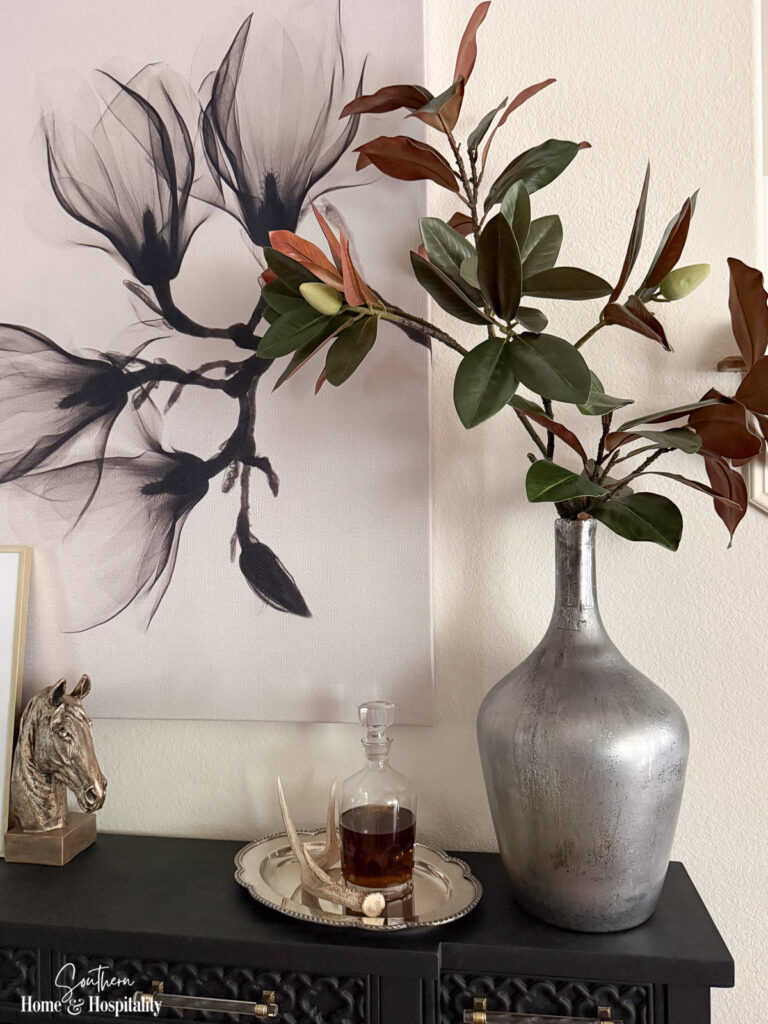 Faux magnolia branches with large green leaves and brown undersides in a fall arrangement