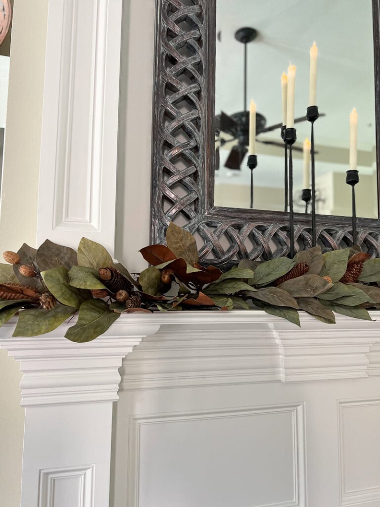 Faux dried magnolia leaves arranged as loose greenery across a fall mantel