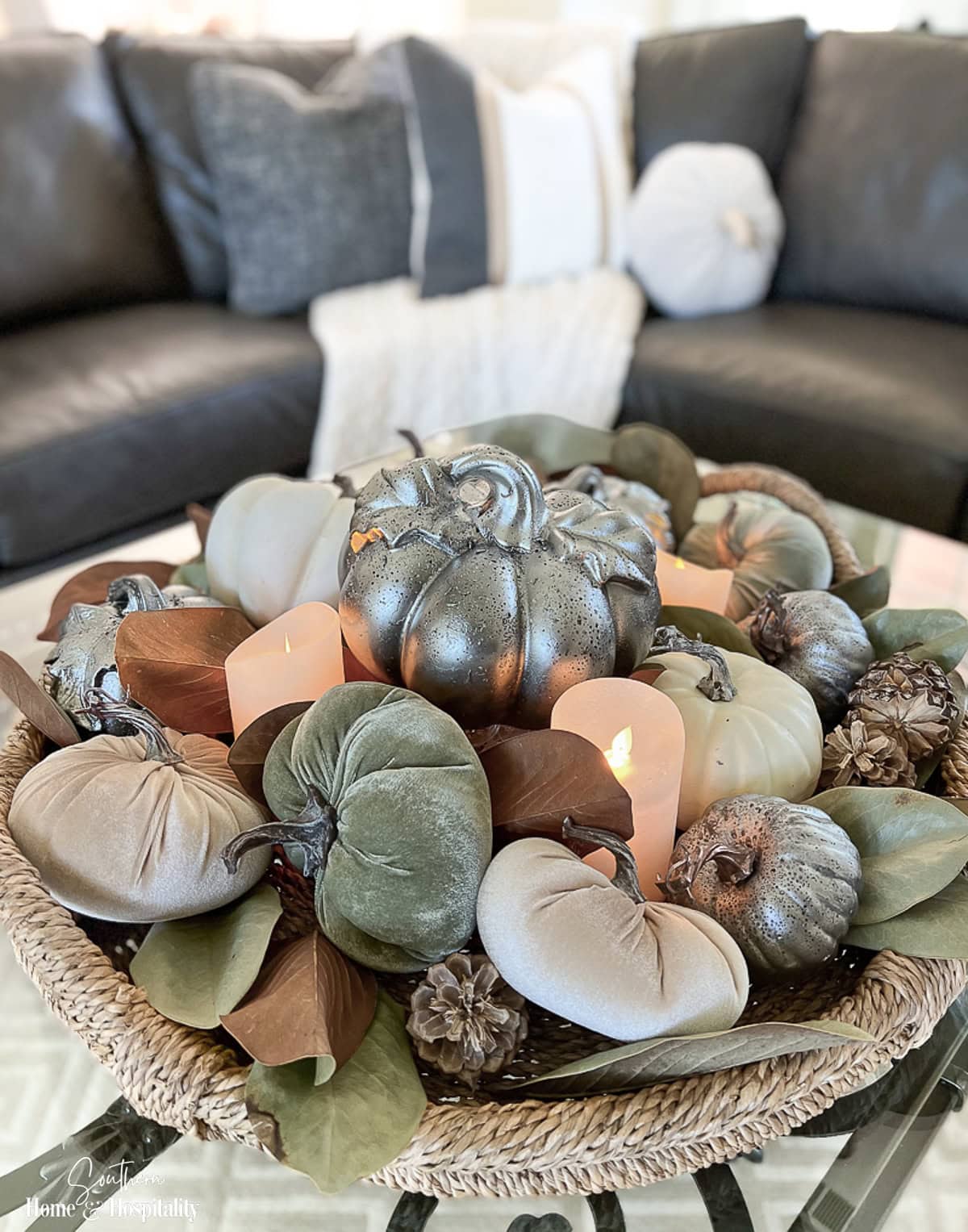 Dried magnolia leaves mixed with pumpkins and pinecones in a fall coffee table arrangement
