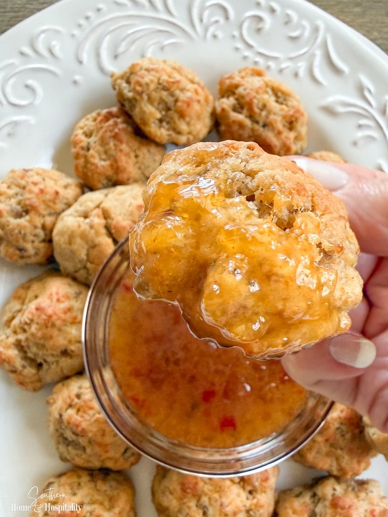 Cream cheese sausage ball being dipped into sweet and tangy pepper jelly-Dijon sauce