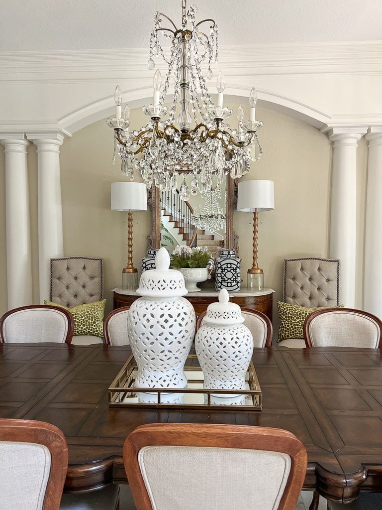 Two white ginger jars grouped on a mirrored tray for a simple centerpiece on a long dining table