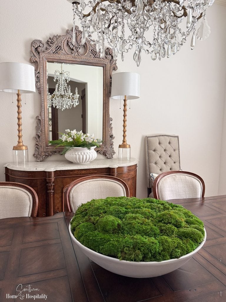 Oversized white bowl filled with green moss as a simple everyday centerpiece on a long wooden dining table